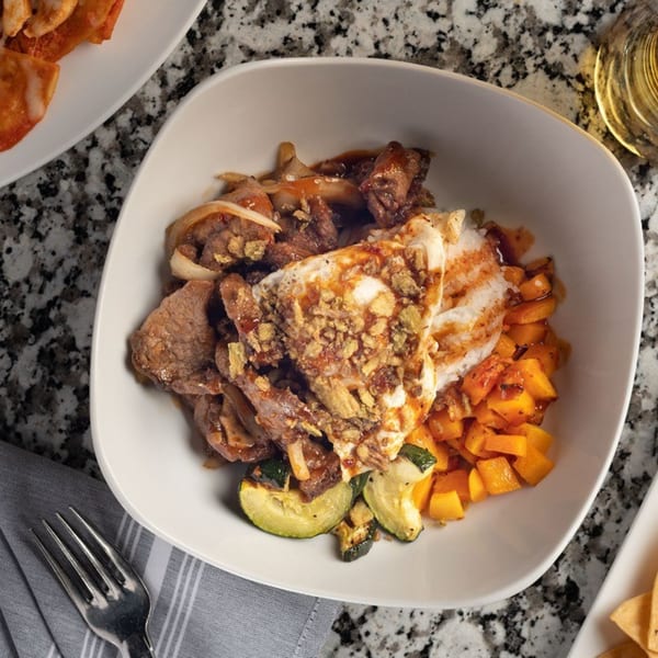 Alma Kitchen's American dish with beef, rice, butternut squash, and zucchini in a white bowl.