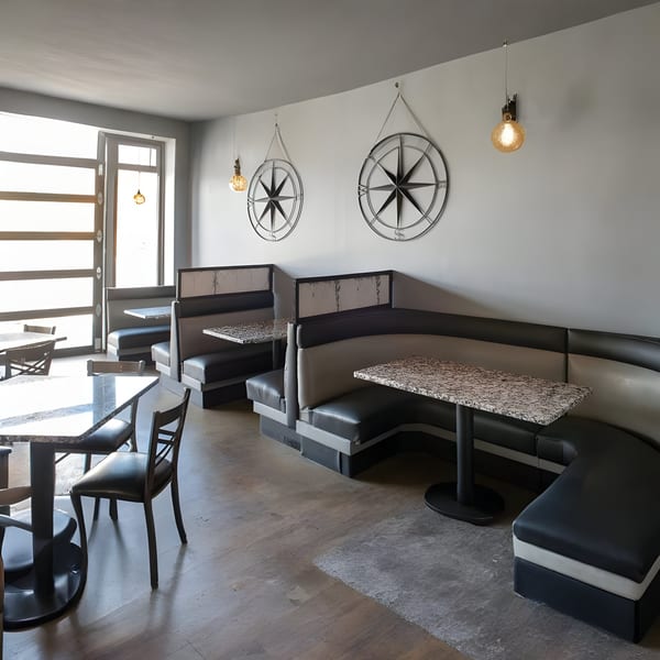 Alma Kitchen's dining area with black and gray booths, granite tables, and compass wall decor.