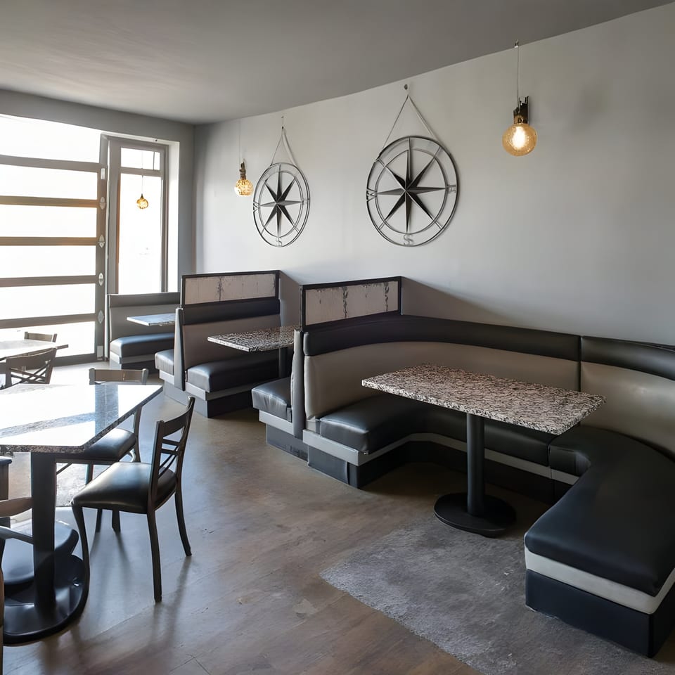 Alma Kitchen's dining area with black and gray booths, granite tables, and compass wall decor.