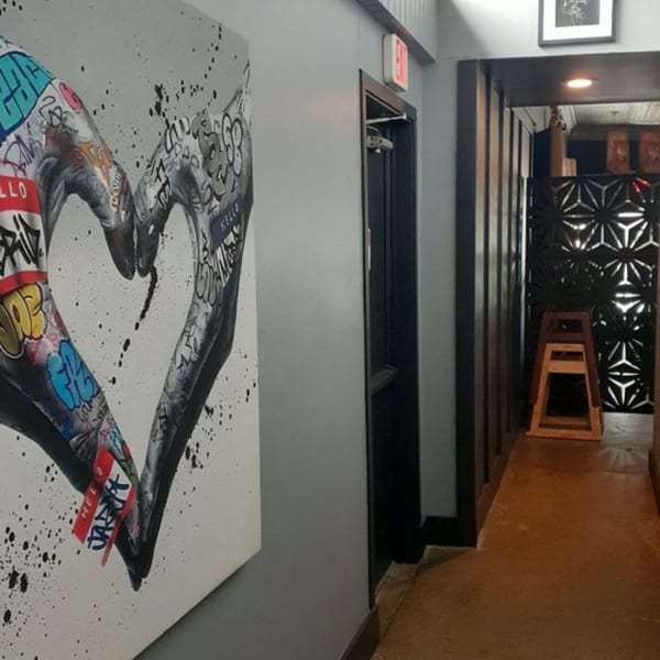 A hallway with a graffiti heart painting on the left and a decorative screen on the right.