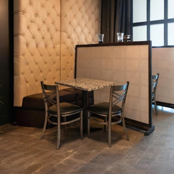 A cozy Alma Kitchen dining area with a tufted booth, granite table, and two chairs.