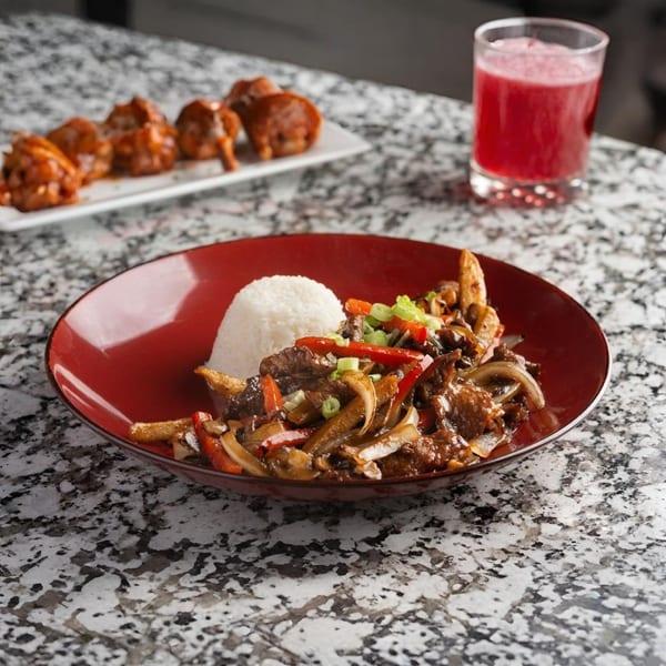 Alma Kitchen's beef stir-fry with rice, a side of dumplings, and a red beverage.